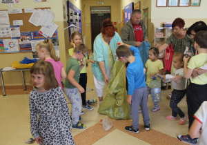 Dzieci i pracownicy przedszkola porządkują korytarz.